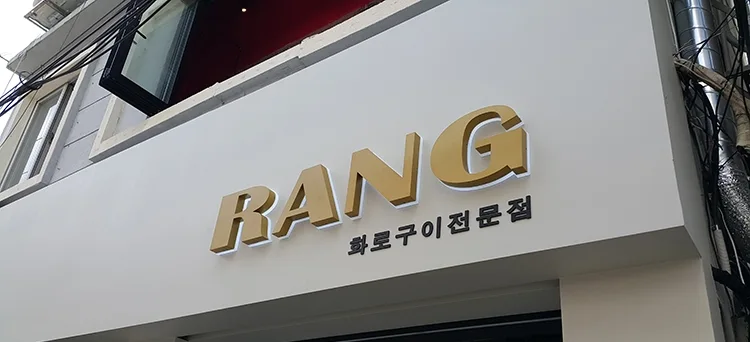  RANG · 흰 바탕 위 금색 상호의 선명한 입체감 · 실제 시공 사진