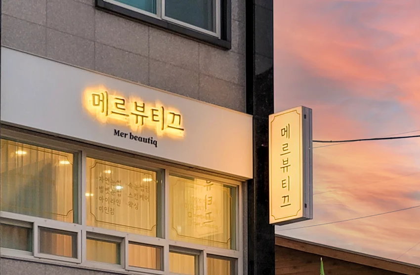  메르뷰티끄 · 상호 문자와 세로 돌출 간판에 켜진 따뜻한 조명 · 실제 시공 사진